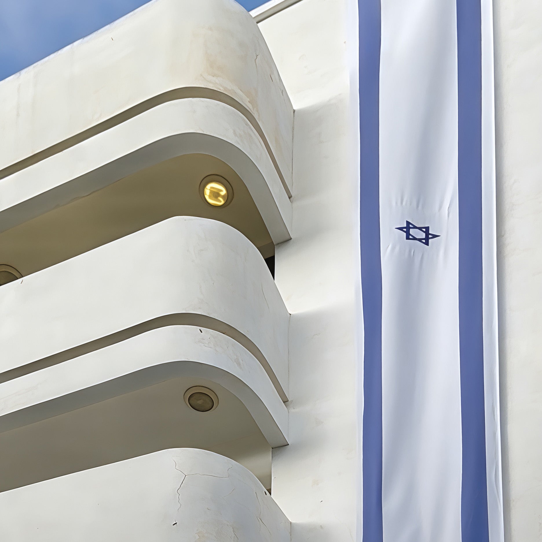Bauhaus at Dizengoff architecture featuring an Israeli flag on a modern building in Tel Aviv.