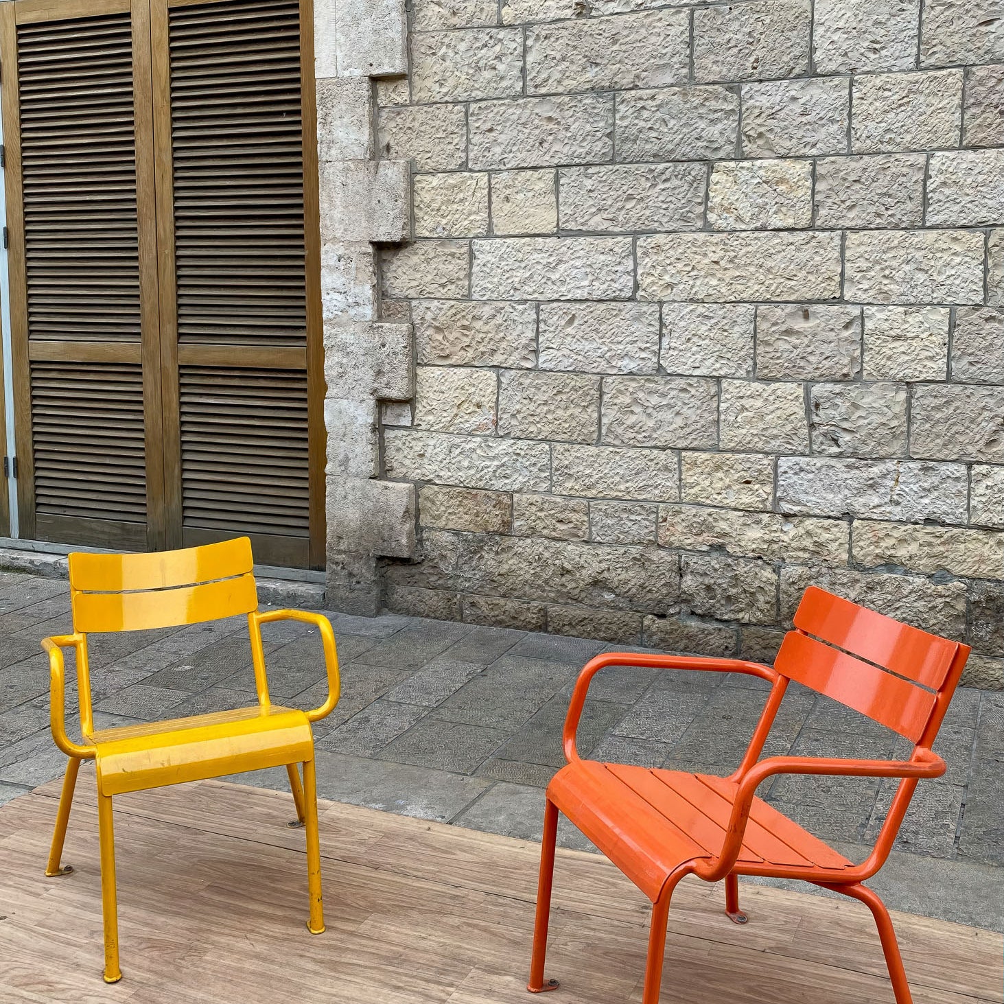 Colorful yellow and orange chairs in front of a stone wall at Jaffa Flea Market in Tel Aviv.