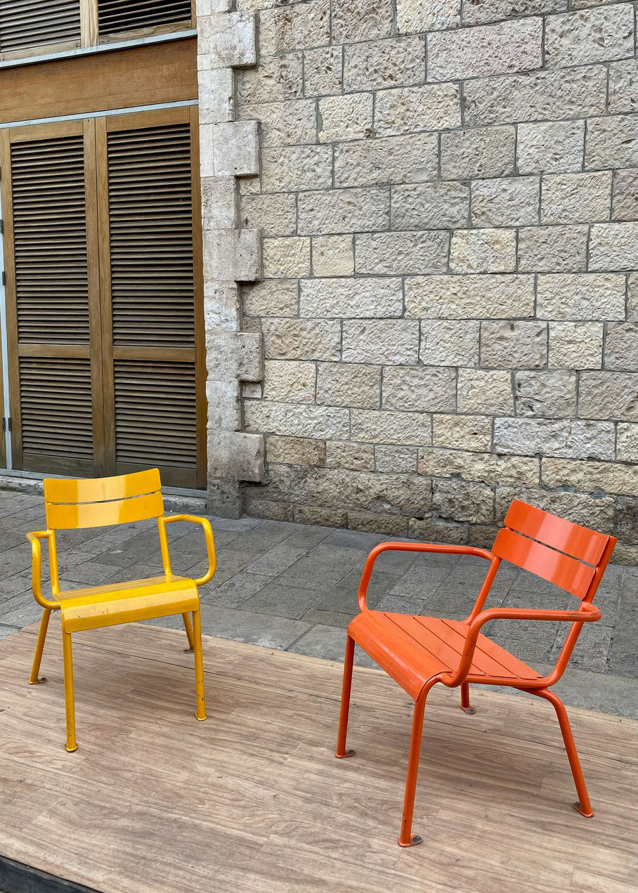 Colorful yellow and orange chairs in front of a stone wall at Jaffa Flea Market in Tel Aviv.