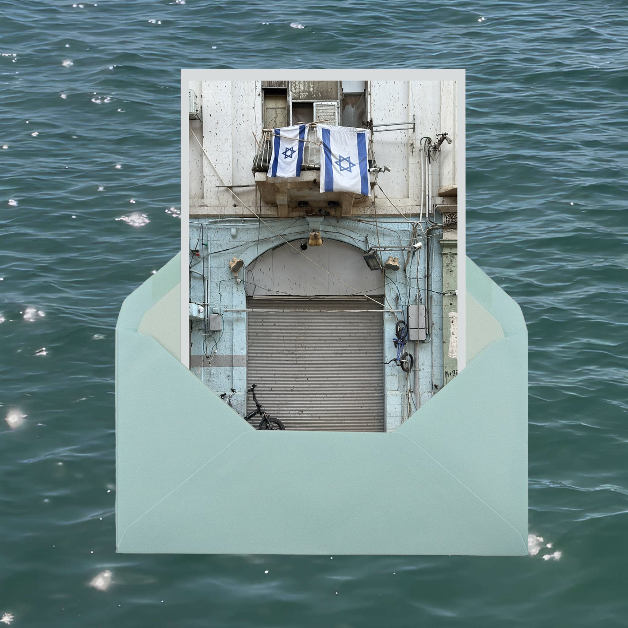 Letter from Tel Aviv photo print of a building with Israeli flags, inside a teal envelope against a water background.