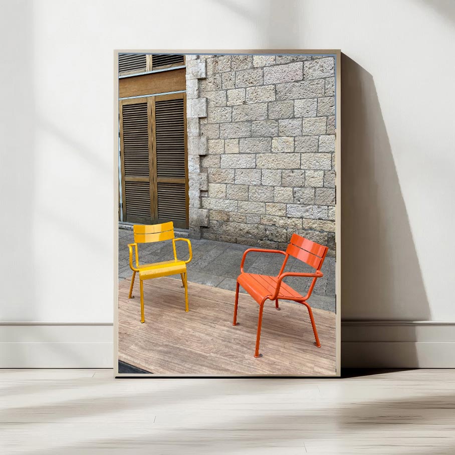 Printed poster featuring vibrant yellow and orange chairs against a textured stone wall.