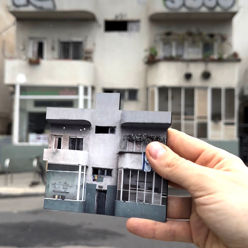 THIS IS TEL AVIV Israel Souvenir — Architecture Miniature held in front of a Tel Aviv building, showcasing urban charm.
